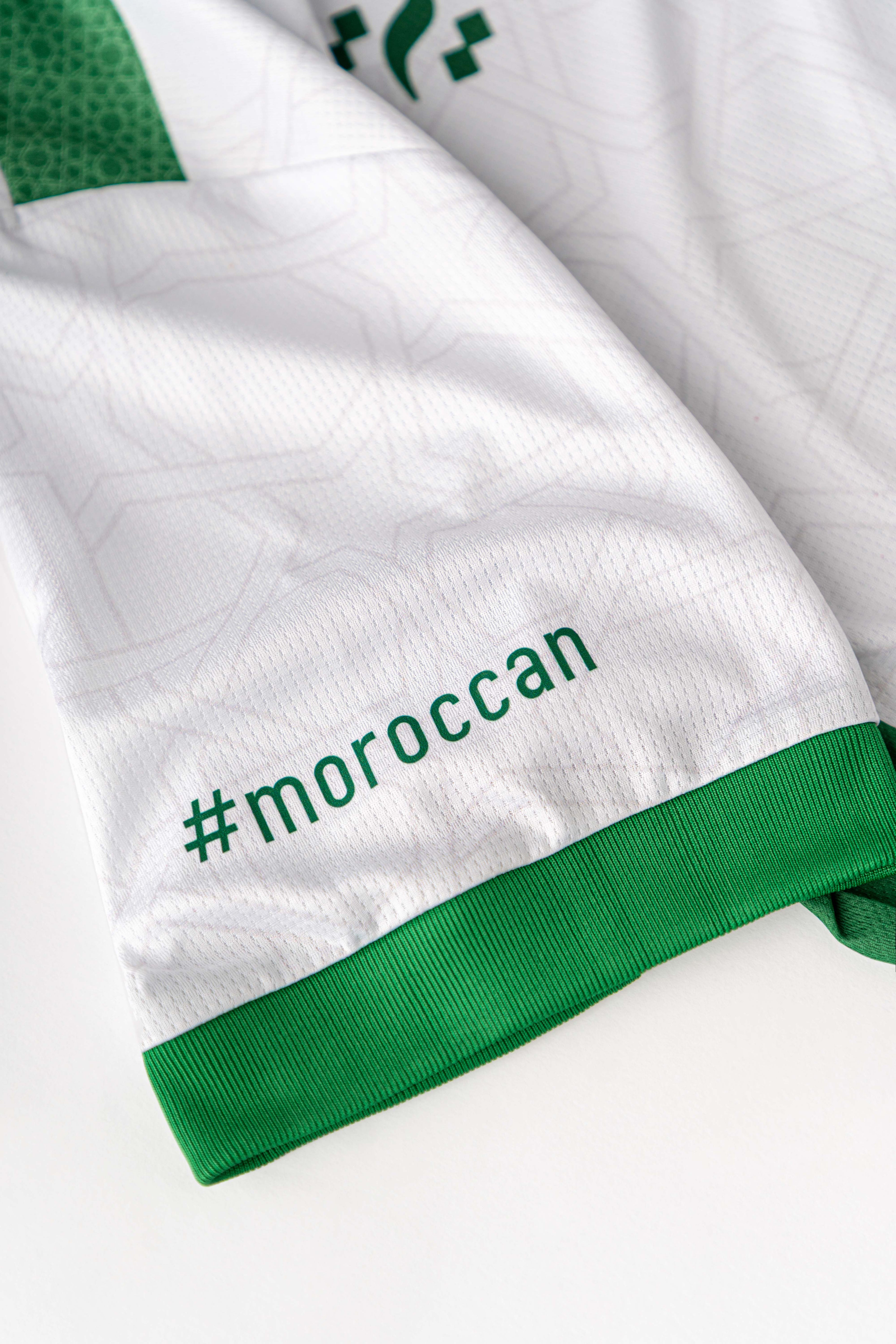 Close-up of the Lions Wear Moroccan AURA jersey sleeve with #morocCAN text and green ribbed cuff — breathable DryMesh fabric detail.